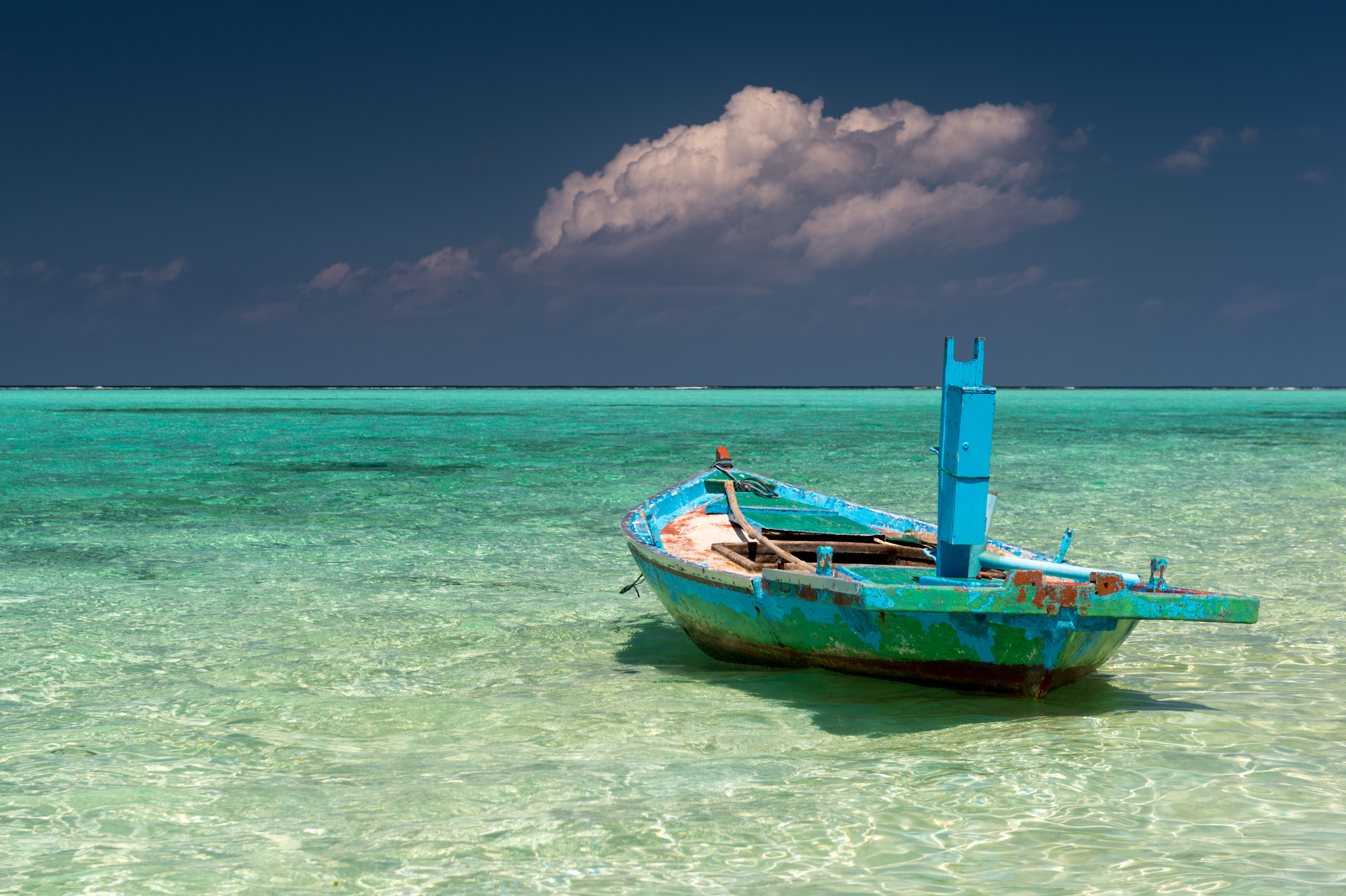 Traditional wooden boat resting in the shallow turquoise lagoon waters off Thoddoo island, Maldives
