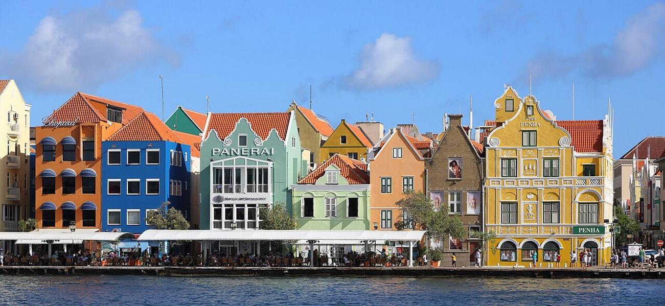 L'odeur saline mÃªlÃ©e aux Ã©pices flotte sur Handelskade, oÃ¹ les faÃ§ades pastel se reflÃ¨tent dans l'eau du port.