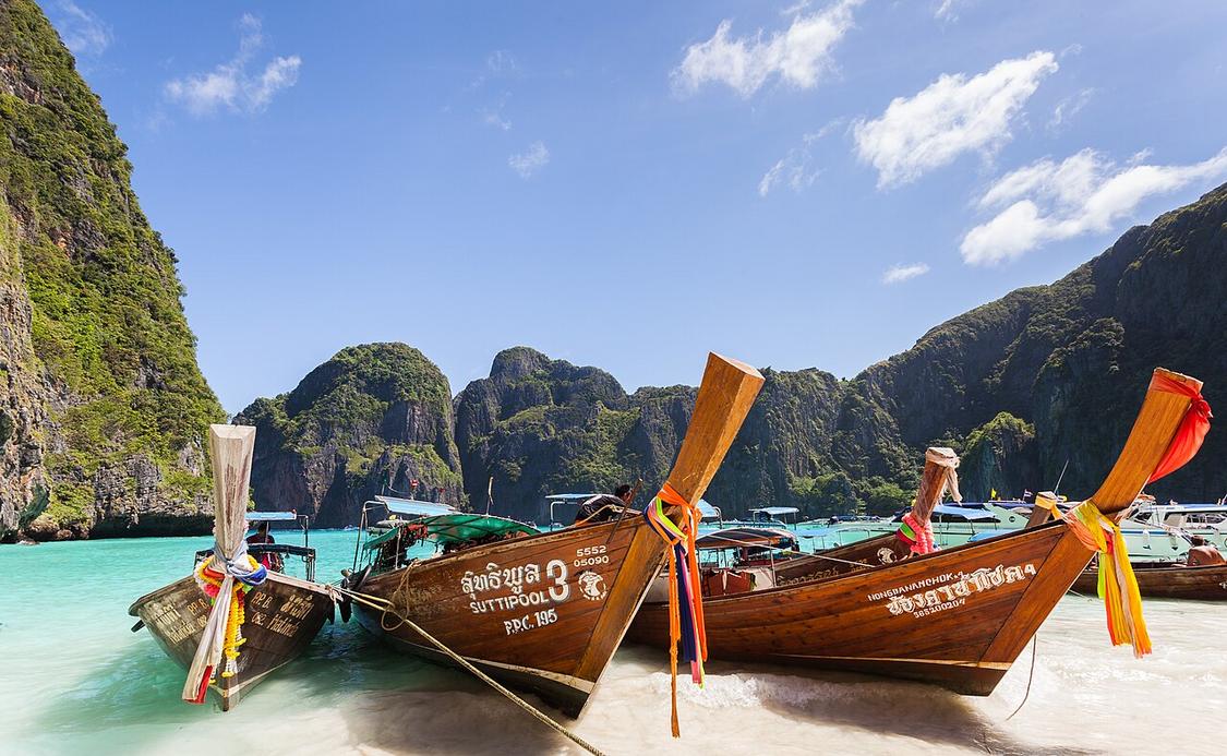The salty breeze mixes with boat engines at Tonsai Bay harbor, where limestone cliffs rise sharply from the water.