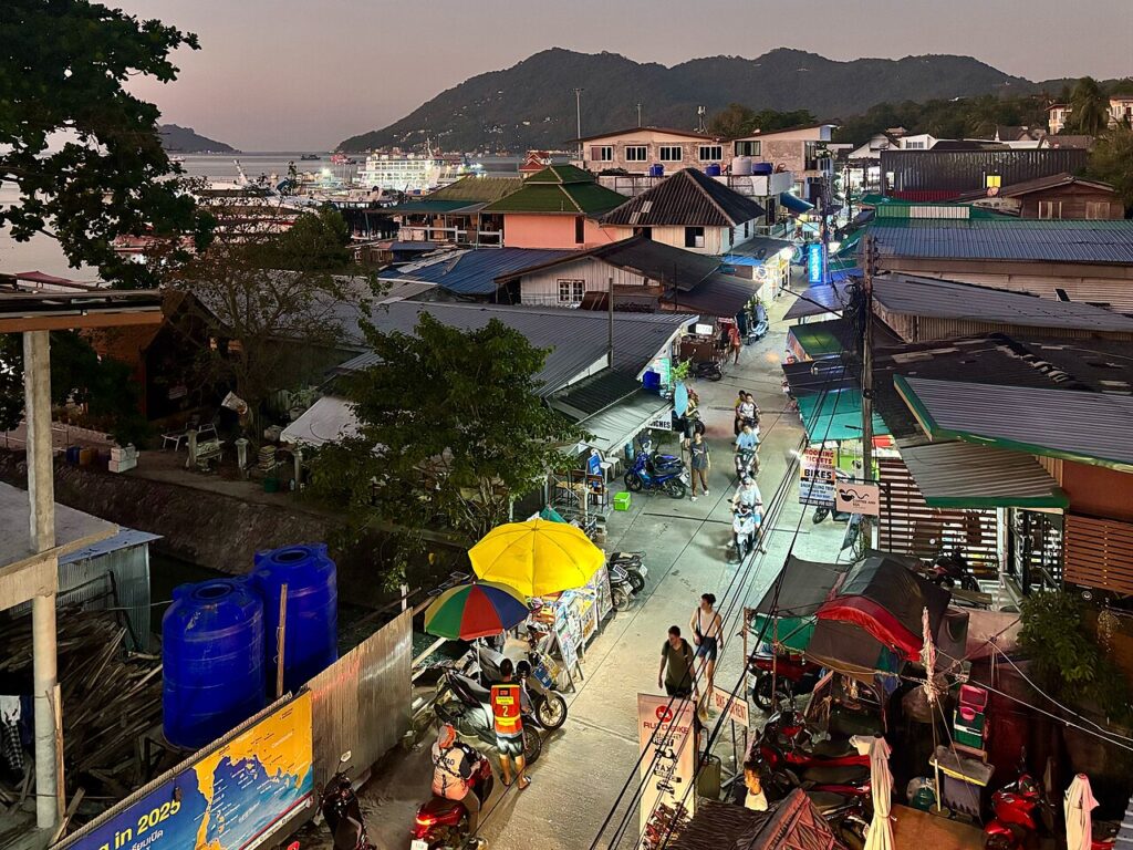 Koh Tao Nightlife: Bars and Nightspots in Thailand 1 Evening street scene in Mae Haad, Koh Tao, with shops, motorbikes and the harbor in the background.