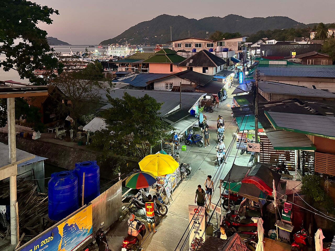 Koh Tao Nightlife: Bars and Nightspots in Thailand 3 Evening street scene in Mae Haad, Koh Tao, with shops, motorbikes and the harbor in the background.