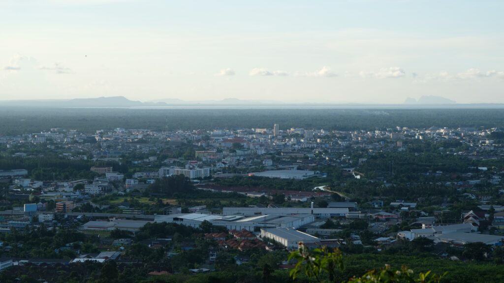Aerial view of Surat Thani city skyline surrounded by greenery at dusk.